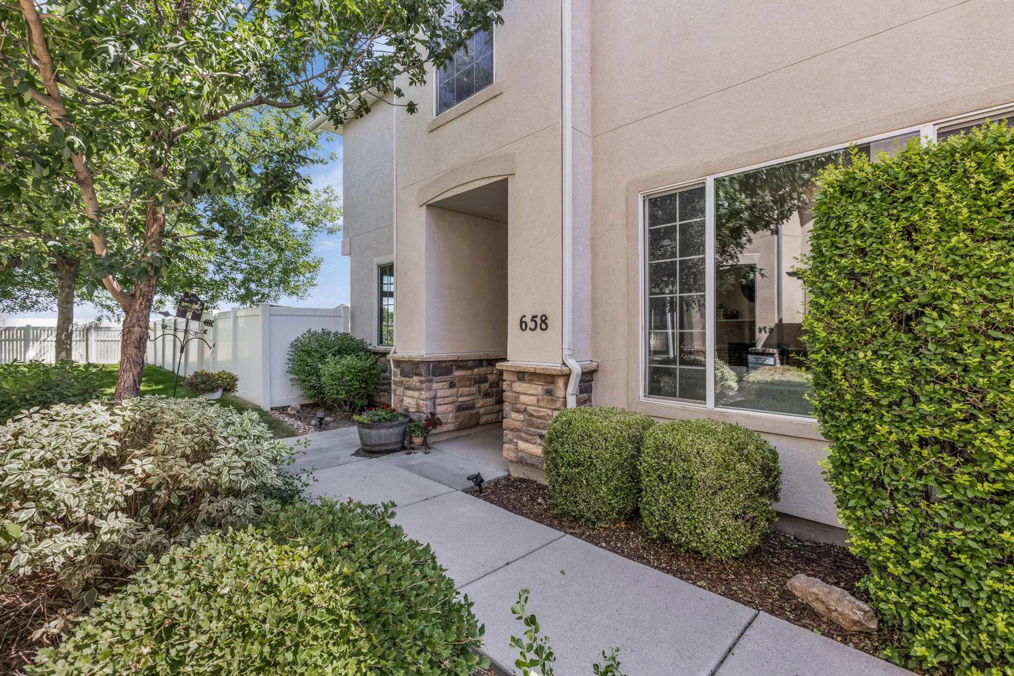 Property exterior featuring a stucco facade with stone veneer accents, an arched entry, and a large multi-pane window