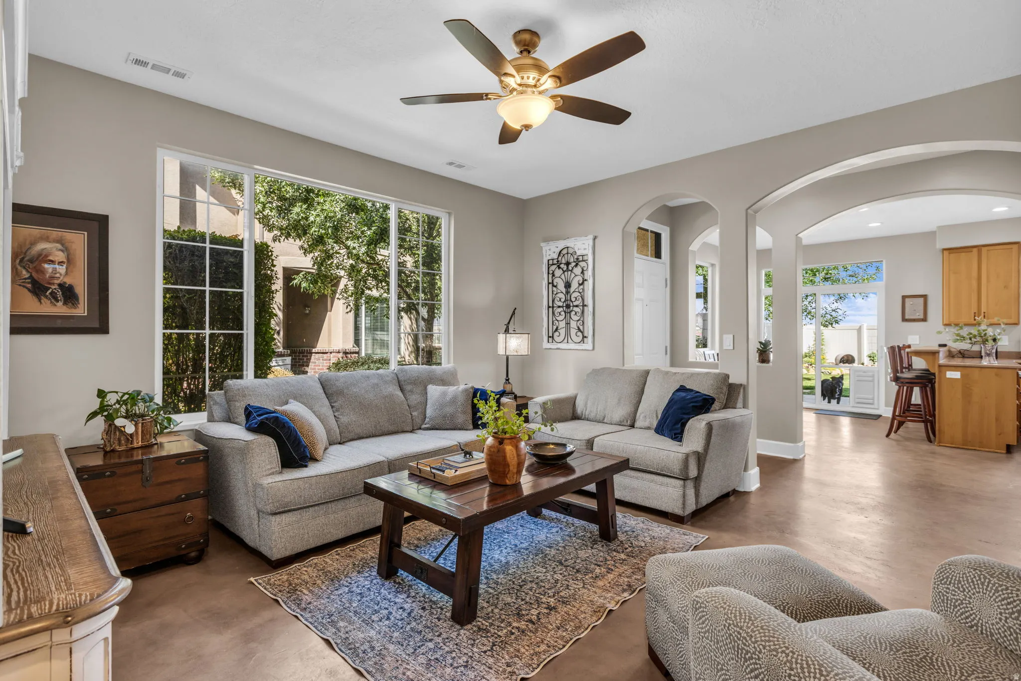 Spacious living area featuring large picture windows, a ceiling fan, and arched doorways