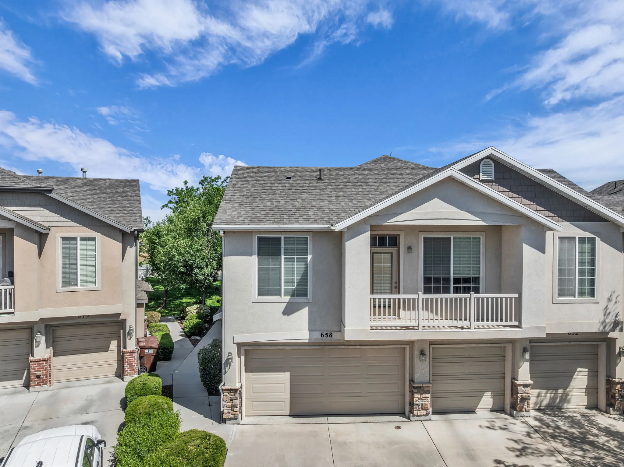 Townhome exterior featuring a neutral stucco finish and a contrasting dark shingle roof
