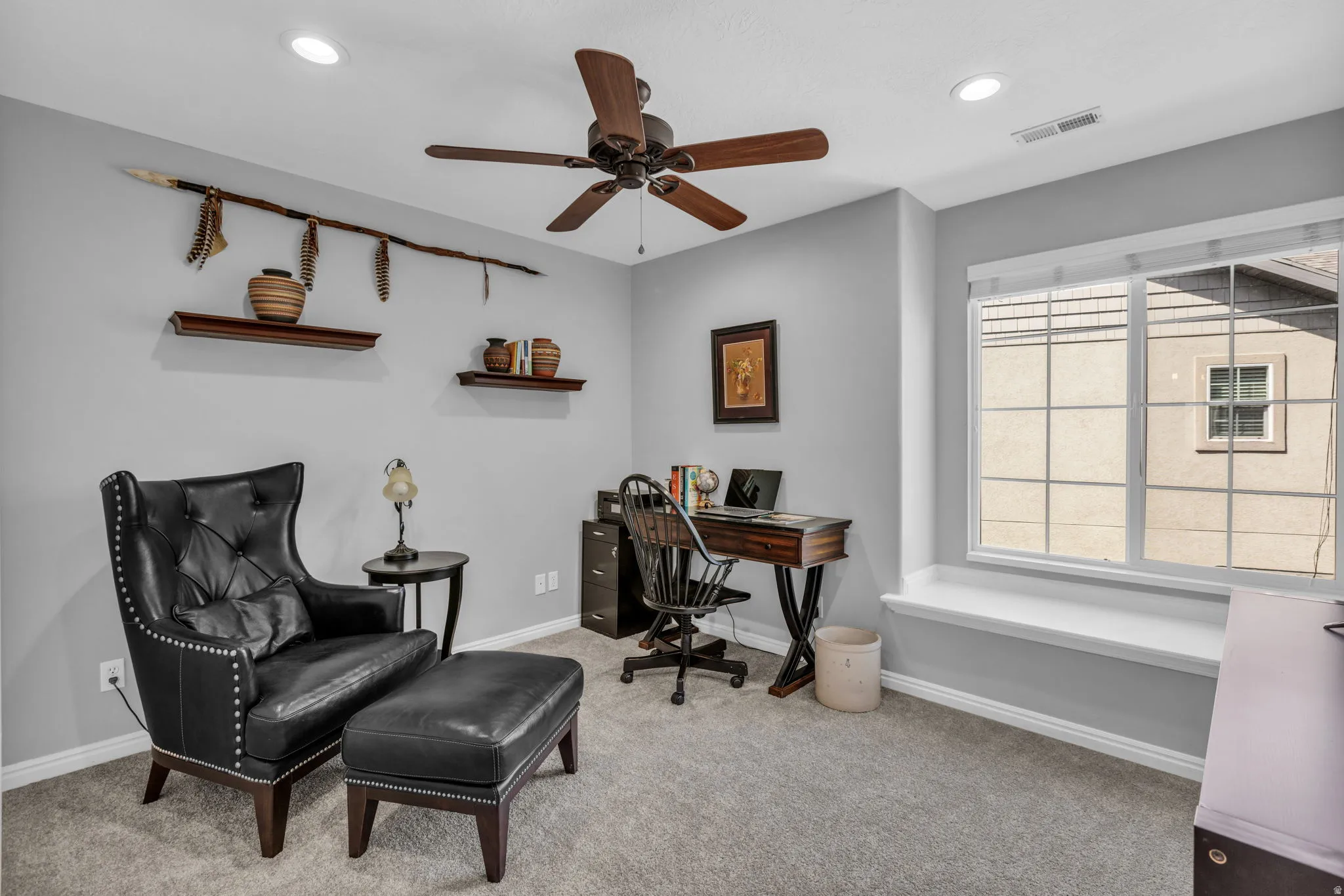 Carpeted room featuring a large window with a built-in window seat, recessed lighting, and a ceiling fan