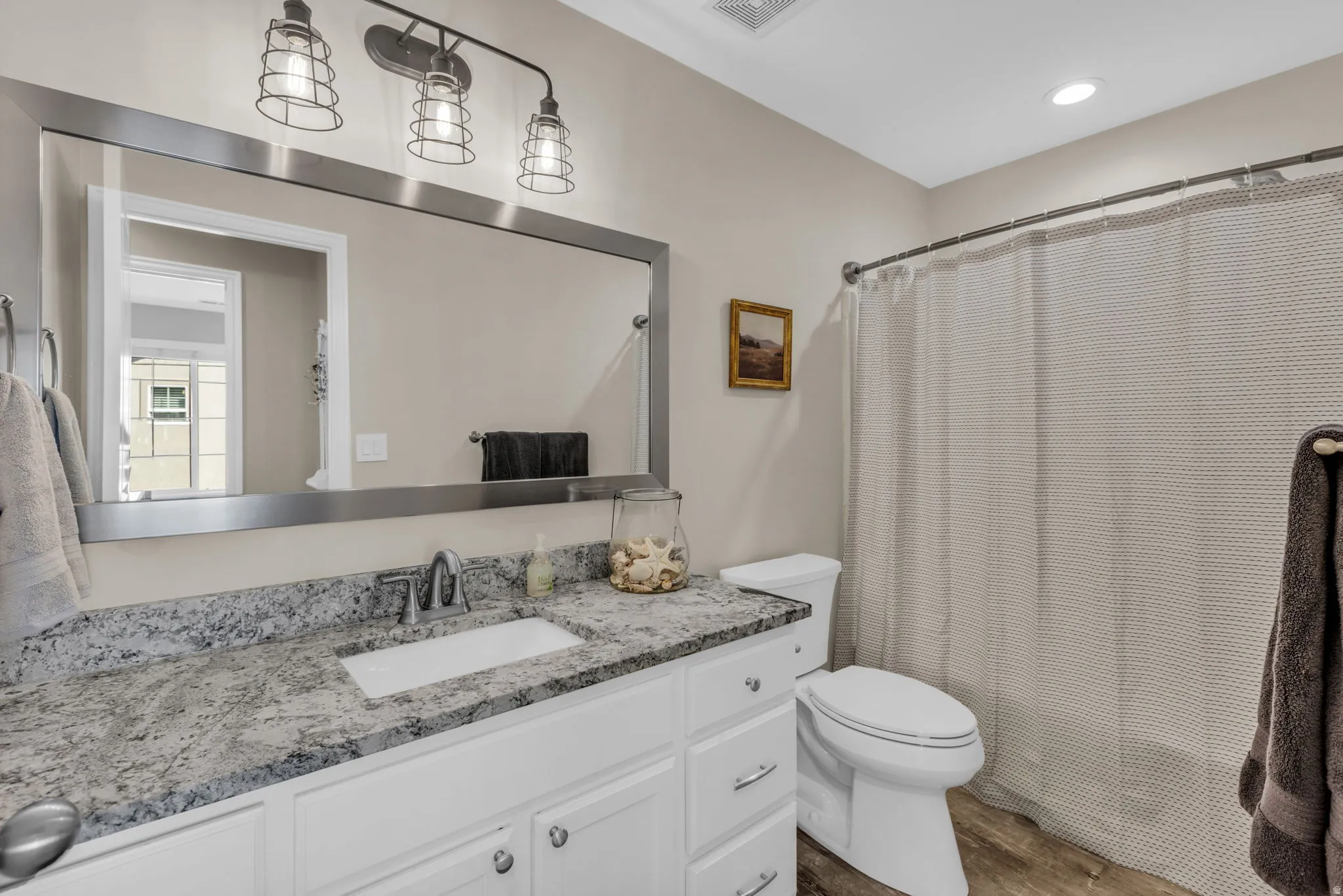 Bathroom featuring a white vanity with a granite countertop, undermount sink, and chrome faucet
