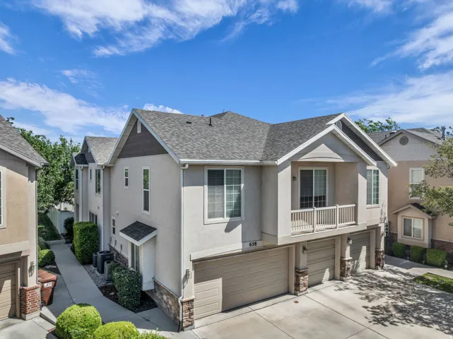 Multi-level townhome featuring a stucco exterior with stone accents