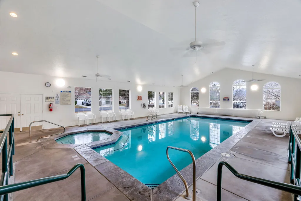Indoor swimming pool featuring an integrated hot tub and vaulted ceilings