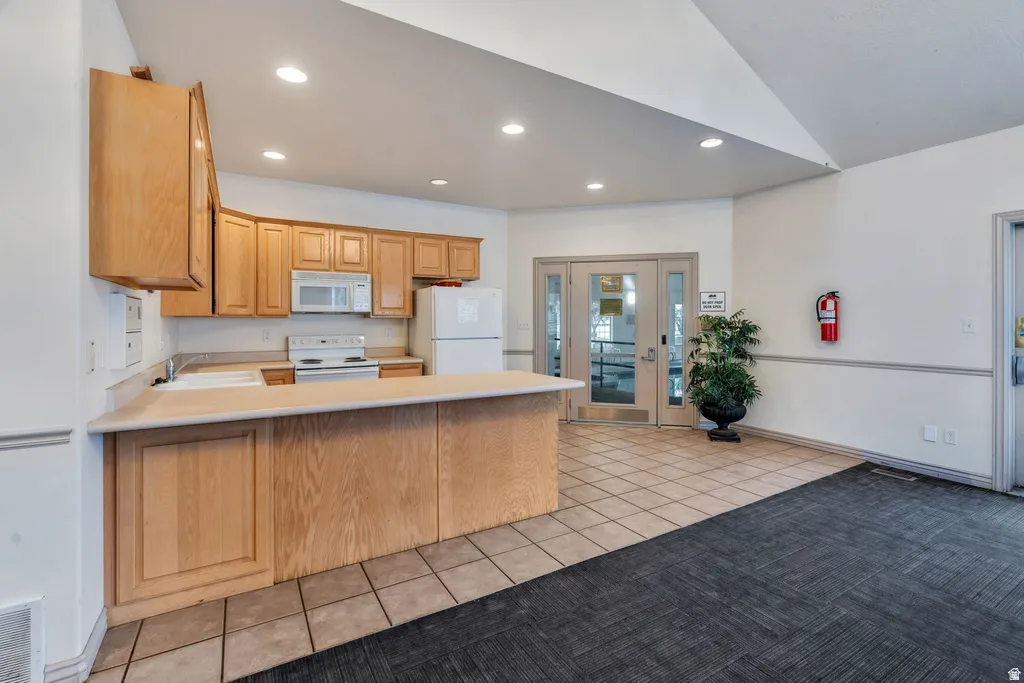 Functional kitchen area with wood-finish cabinetry, white appliances, and a light-toned countertop