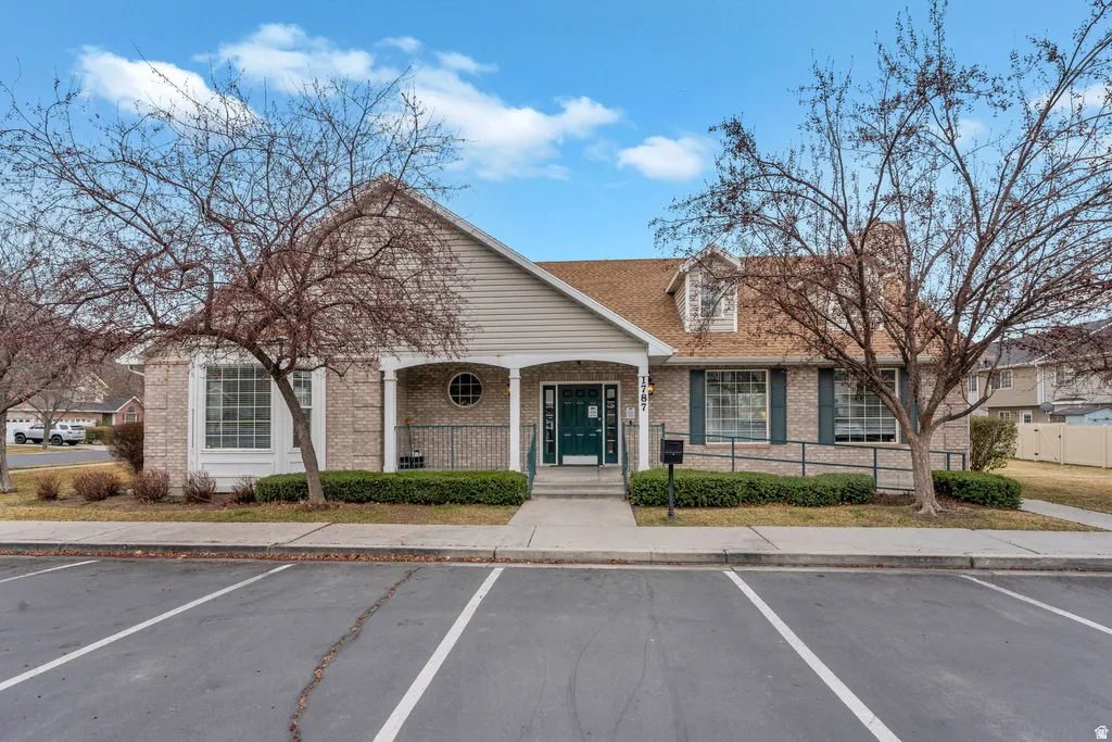 Brick and siding building featuring a covered entryway with columns, a circular window, and dormer accents