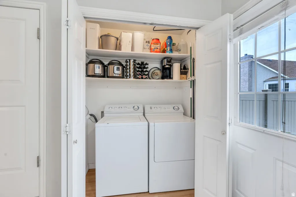 Dedicated laundry closet featuring integrated shelving, and wood-finish flooring