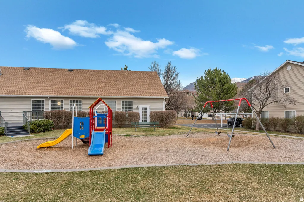 Community playground featuring a colorful play structure with slides, a swing set, and a wood chip surface