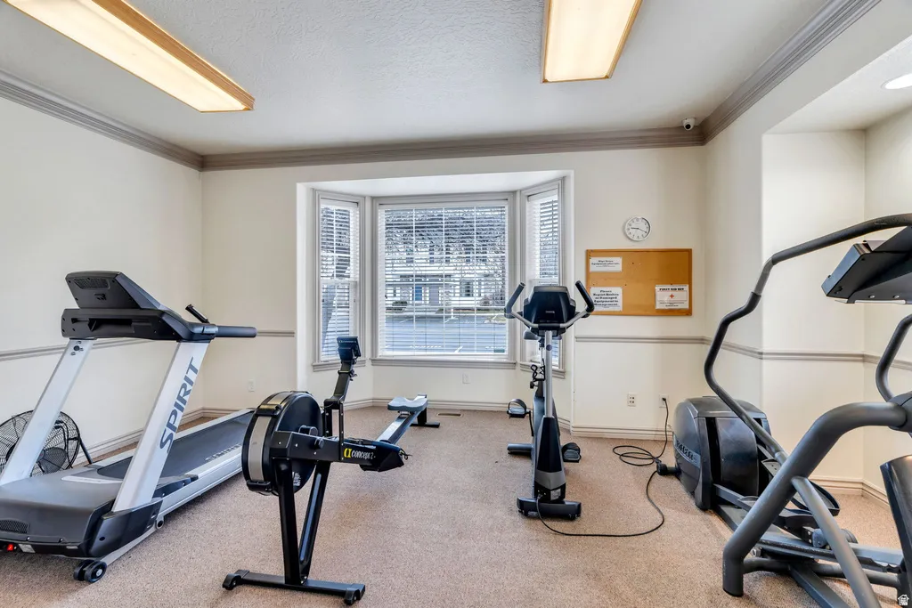 Dedicated fitness area featuring a bay window, recessed lighting, crown molding, and neutral carpeting