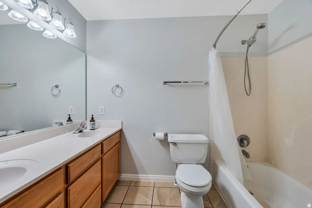 Bathroom featuring a single vanity with wood-finish cabinetry, a large wall-mounted mirror, overhead vanity lighting, a toilet, and a combined shower and bathtub