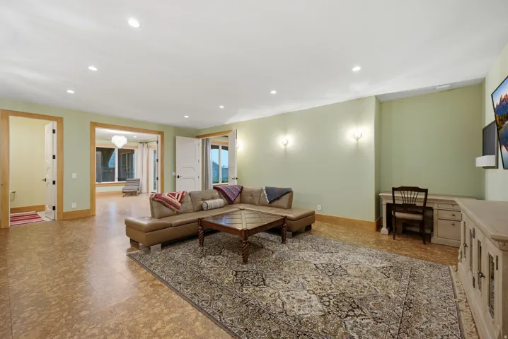 Spacious recreation room featuring recessed lighting, light green walls, wood-finish flooring, and multiple doorways with solid panel doors