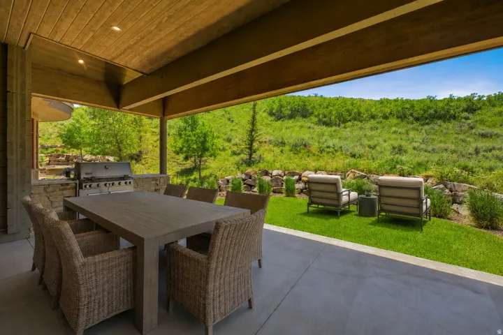 Covered patio featuring a built-in barbecue grill, stone-clad outdoor kitchen, wood-finish ceiling, and recessed lighting