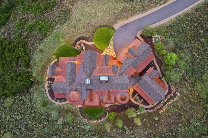 Expansive property featuring a multi-gabled shingle roof, a circular driveway, and a terraced landscape with manicured lawns