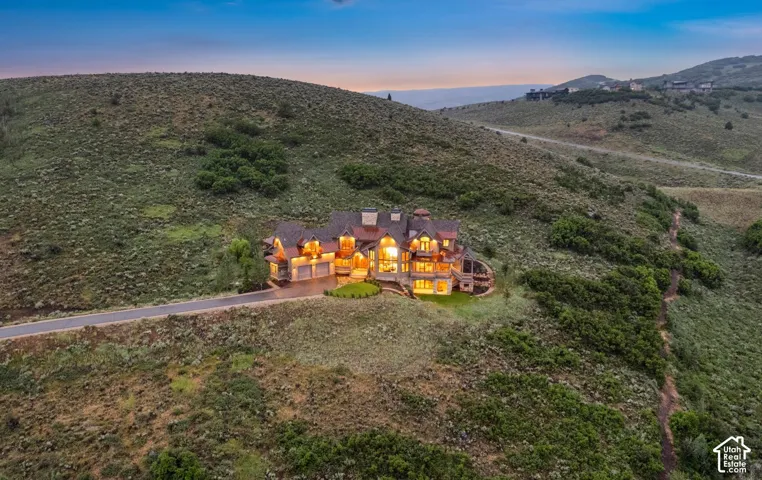 Multi-level estate featuring a stone and timber exterior, complex roofline, attached multi-car garage, and expansive hillside placement