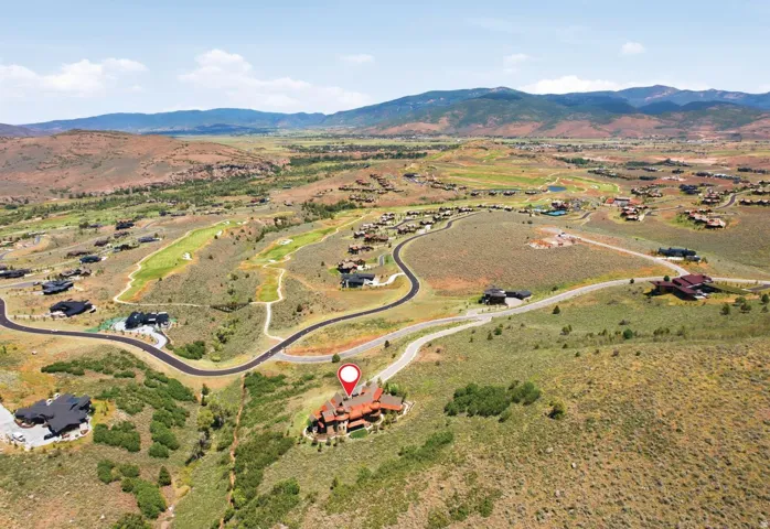 Expansive aerial perspective showcasing a property surrounded by rolling terrain and distant mountains