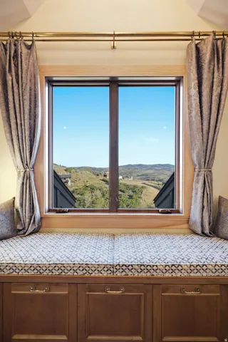 Window seat with built-in cabinetry and upholstered cushions, showcasing a hillside and distant structures