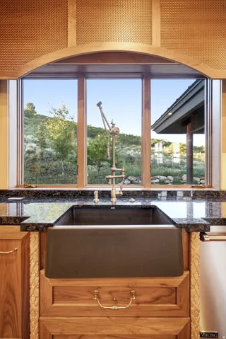 Farmhouse sink with a vintage-style faucet, set into dark granite countertops