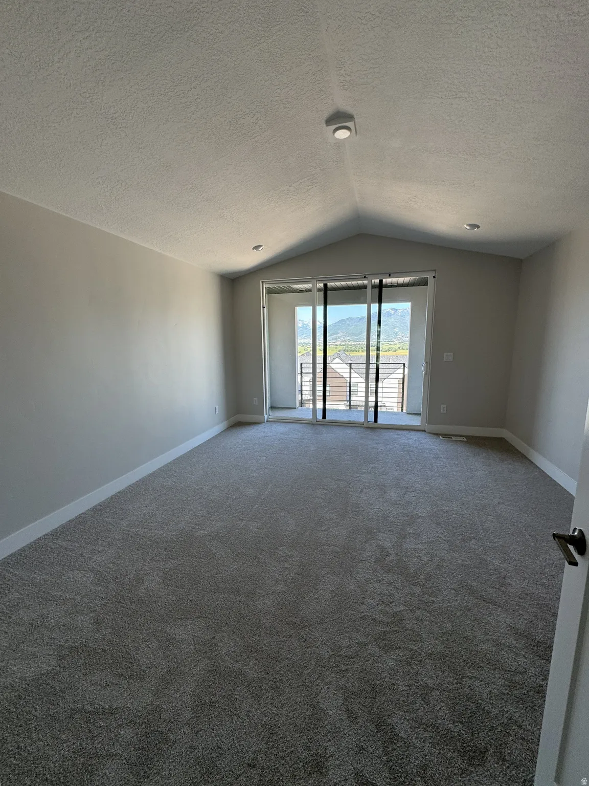 Spacious room featuring vaulted ceilings, recessed lighting, and soft gray carpeting