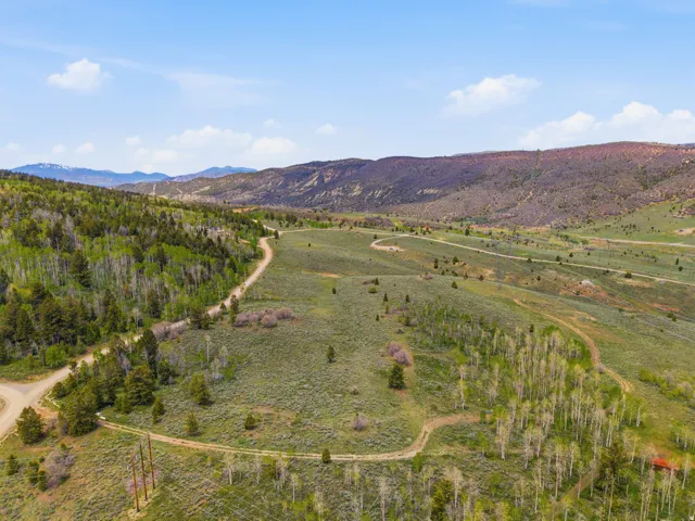Expansive mountain landscape featuring rolling terrain and multiple unpaved roads