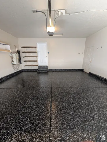 Garage featuring an epoxy floor coating, built-in shelving, two interior doors, and overhead lighting