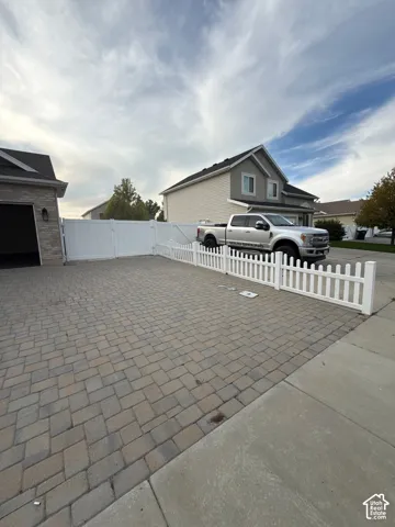 Paver driveway with a white picket fence and a privacy gate