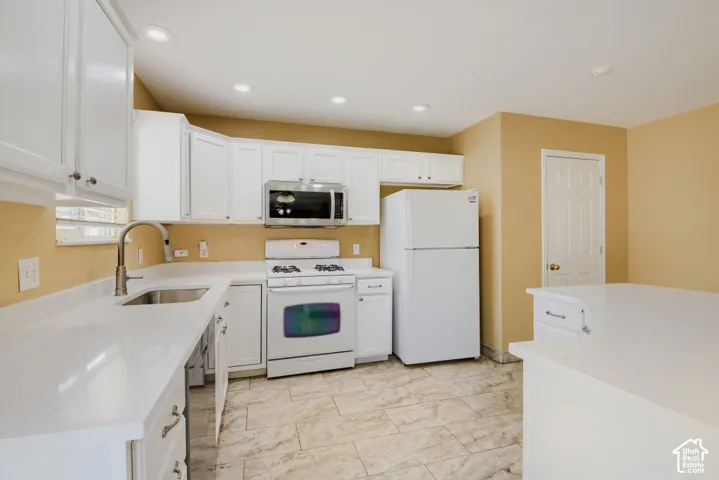 Kitchen featuring white cabinetry, light-colored countertops, stainless steel microwave, and tile flooring