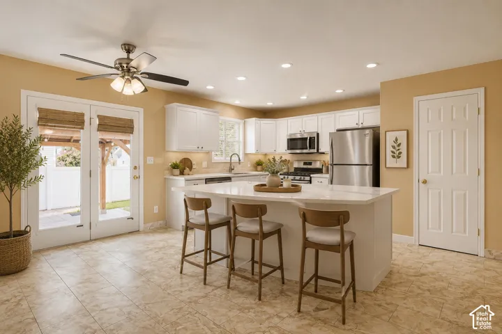 Kitchen featuring a central island with a light-toned countertop, white cabinetry, stainless steel appliances, and recessed lighting