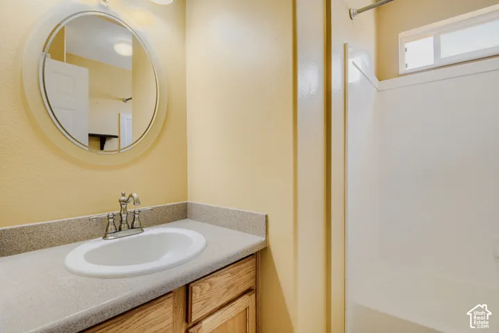 Bathroom featuring a vanity with an integrated sink, brushed nickel faucet, and wood-finish cabinetry