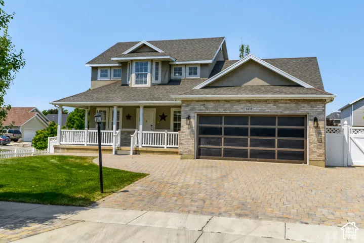 Stone and siding exterior with a covered front porch featuring white railing and columns