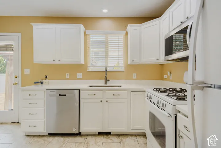 Kitchen featuring white cabinetry, light-toned countertops, tile flooring, a stainless steel dishwasher, and a built-in microwave