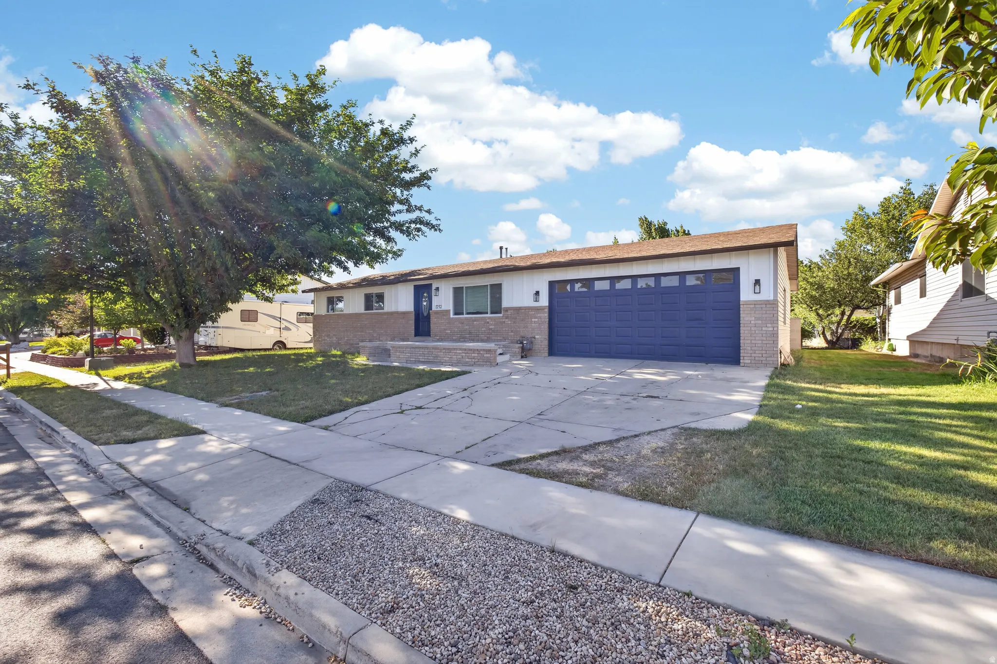 Ranch-style exterior featuring a blue garage door and stone veneer accents