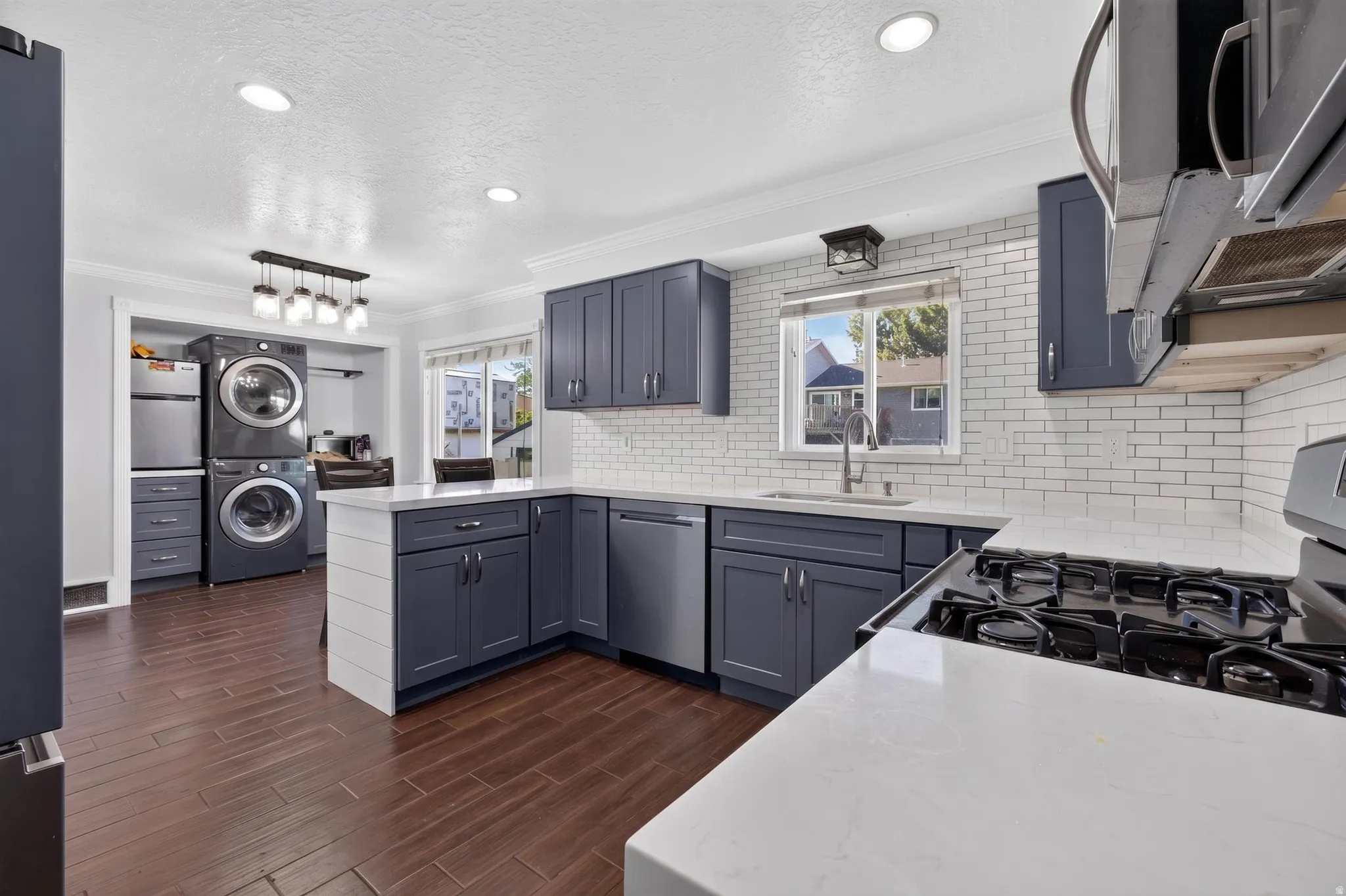 Modern kitchen featuring dark-hued cabinetry, white subway tile backsplash, and light-toned countertops