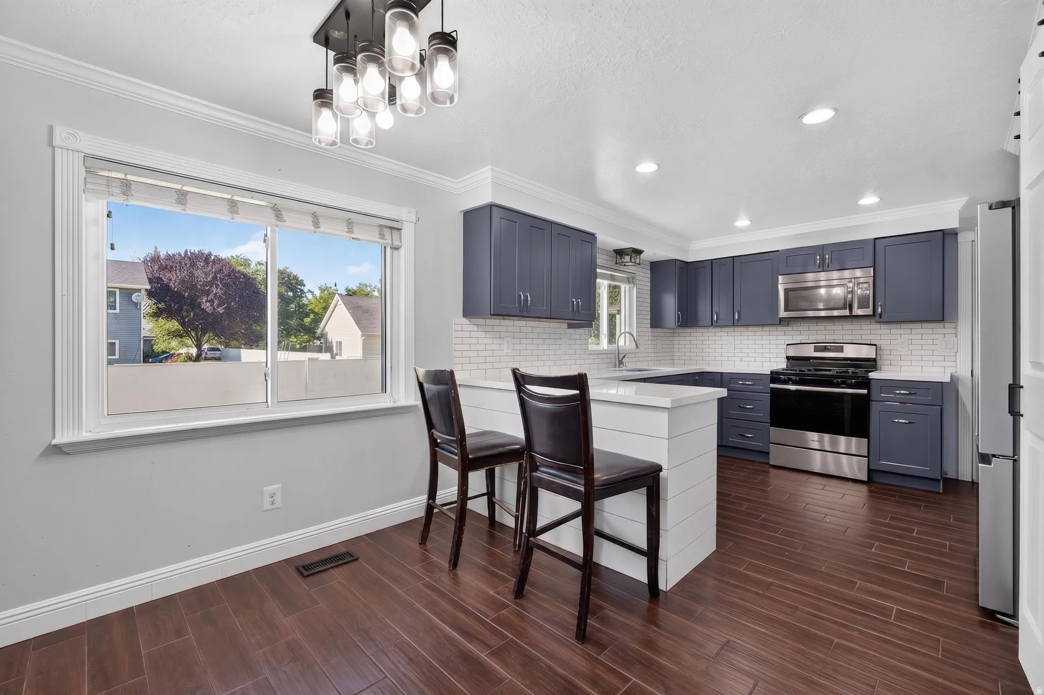 Contemporary kitchen featuring dark blue cabinetry, stainless steel appliances, and a white subway tile backsplash