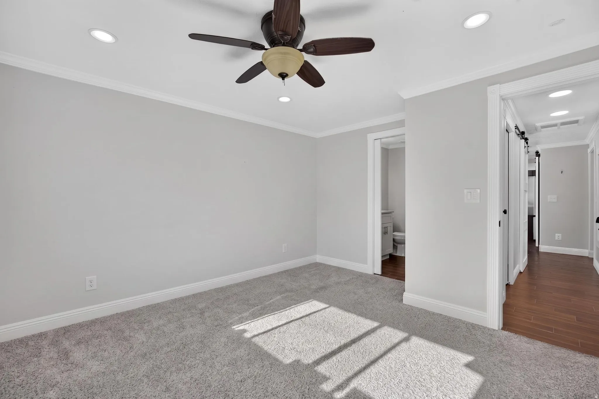 Carpeted room featuring a ceiling fan with integrated lighting, recessed ceiling lights, and crown molding
