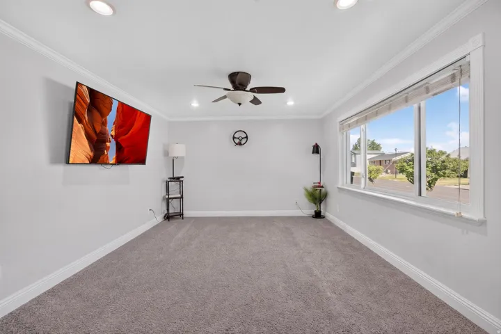 Spacious room featuring light gray walls, plush gray carpeting, white crown molding, and recessed lighting