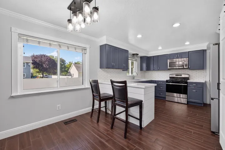 Contemporary kitchen featuring dark blue cabinetry, stainless steel appliances, and a white subway tile backsplash
