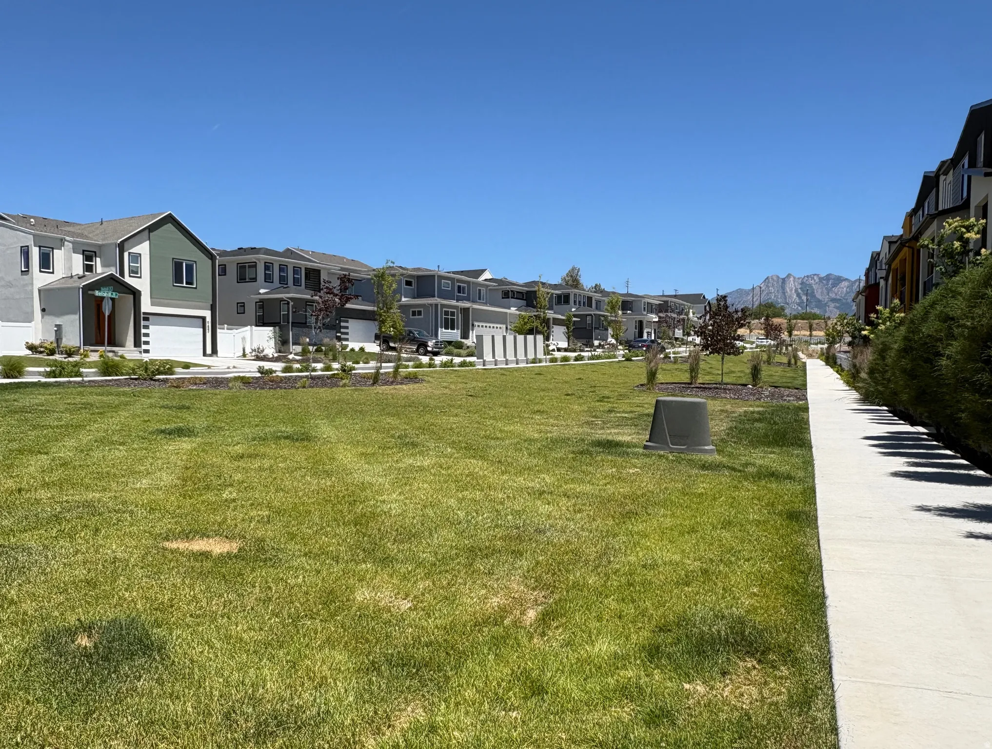 Expansive green space featuring a concrete pathway and distant mountain scenery