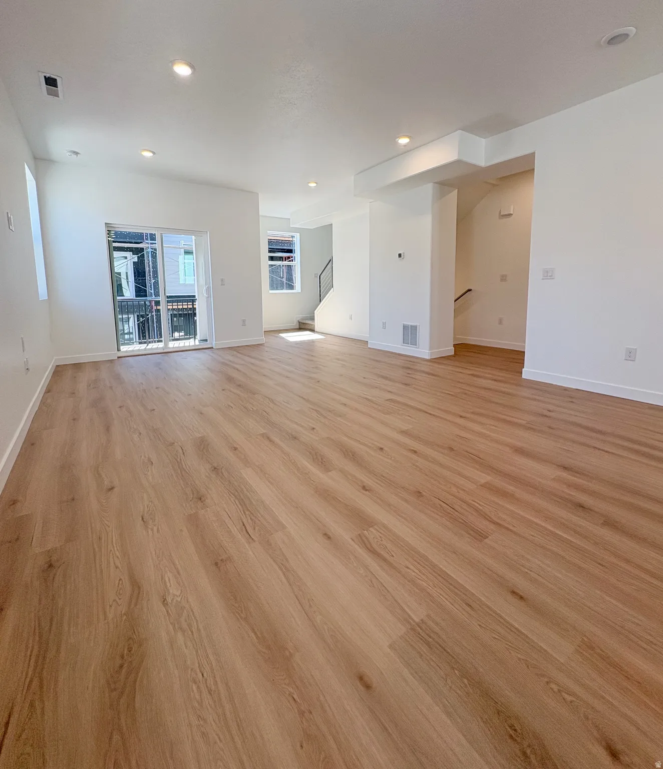 Spacious open-concept interior featuring light wood-finish flooring throughout