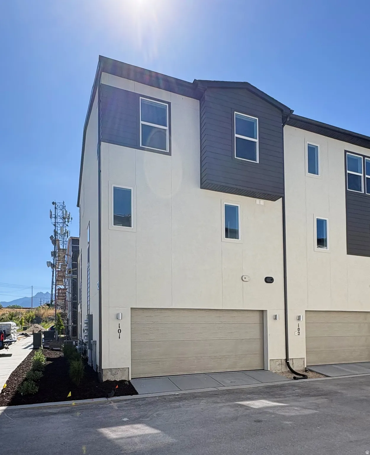 Contemporary townhome exterior featuring light-colored siding and dark horizontal siding accents