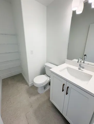 Bathroom featuring a white vanity with bronze hardware, integrated sink, and stone-finish countertop