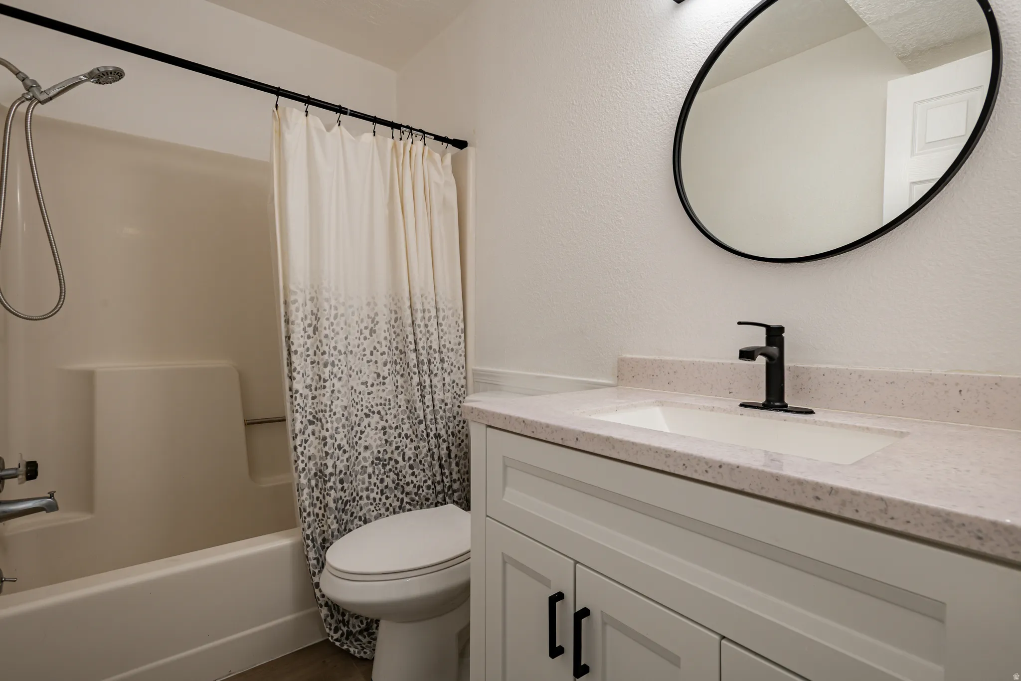 Bathroom featuring a white vanity with shaker-style doors, black hardware, and a light-toned countertop
