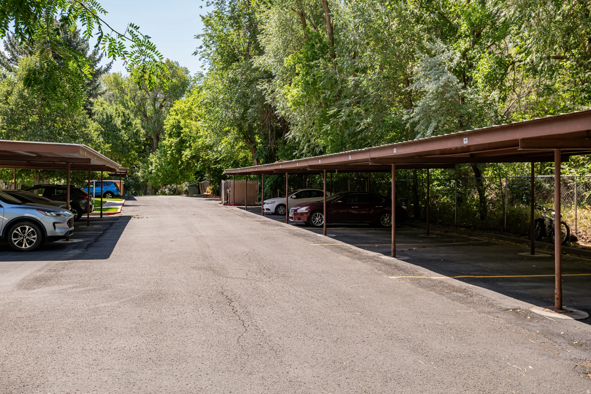 Paved parking area featuring multiple covered carports with brown metal structures