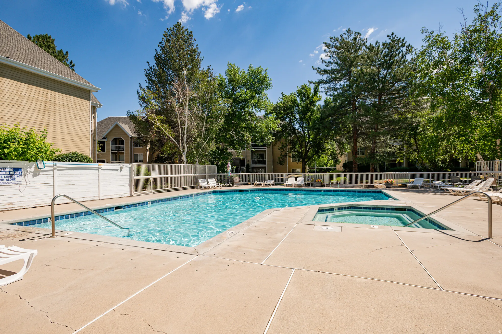 Outdoor swimming pool with integrated spa and surrounding concrete decking