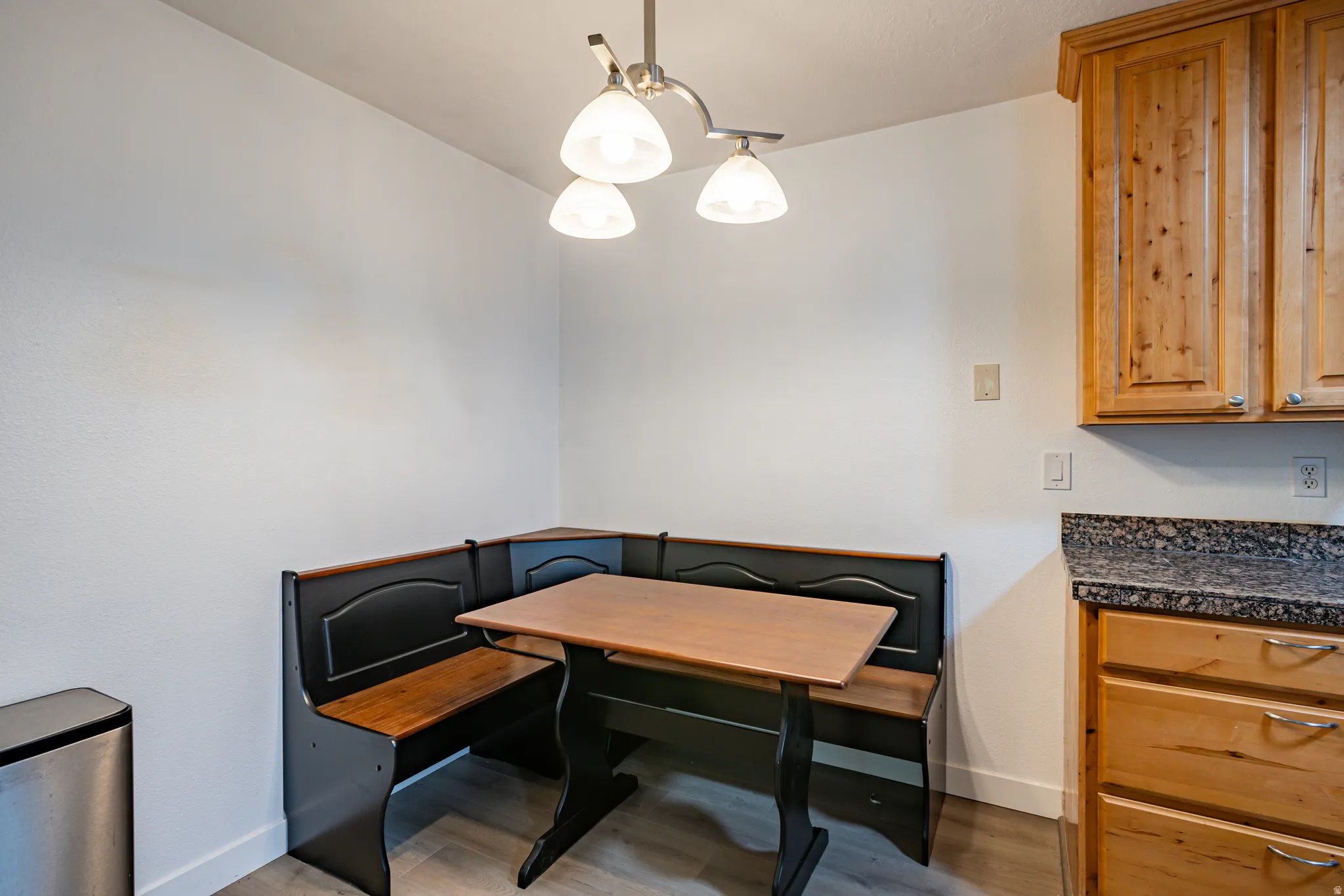 Built-in breakfast nook with a wood-finish table and seating, illuminated by an overhead pendant light fixture