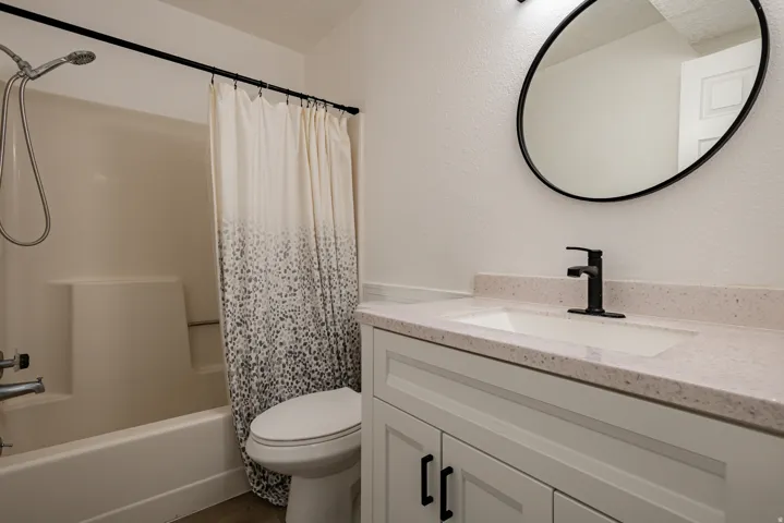 Bathroom featuring a white vanity with shaker-style doors, black hardware, and a light-toned countertop