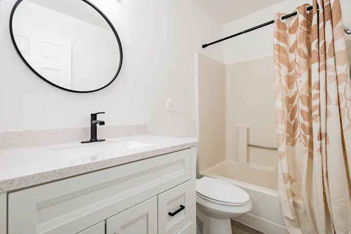 Bathroom featuring a white vanity with flat-panel doors, a white countertop with an integrated sink, and a matte black single-handle faucet