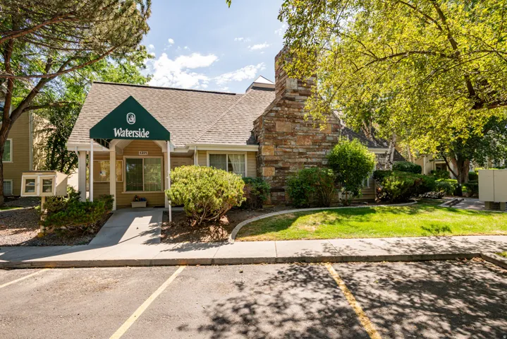 Waterside building featuring a gabled roof, stone chimney, and a green fabric awning