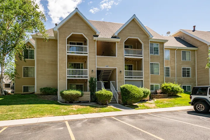 Multi-level condominium building featuring tan siding and multiple balconies with white railings