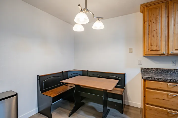 Built-in breakfast nook with a wood-finish table and seating, illuminated by an overhead pendant light fixture