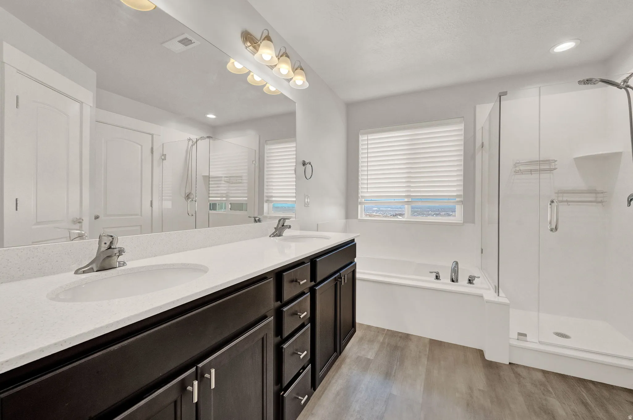 Spacious bathroom featuring a double vanity with stone countertops, dark wood cabinetry, and dual undermount sinks
