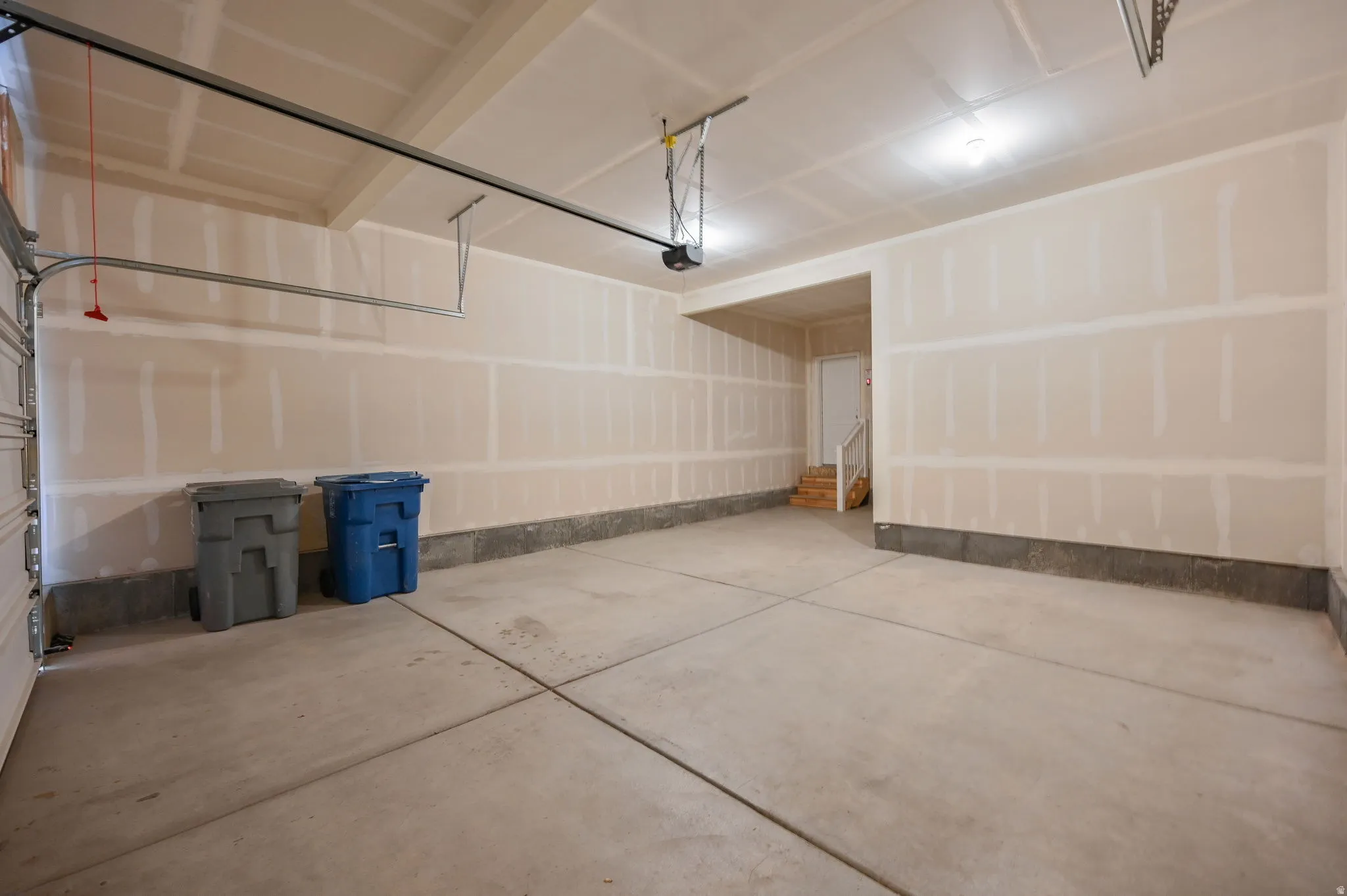 Spacious garage with concrete flooring, automatic garage door opener, and unfinished drywall